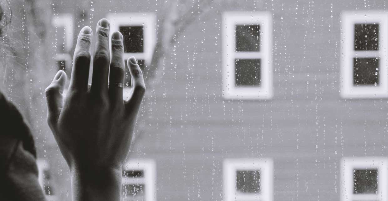 Rainy day - worried woman looking outside window