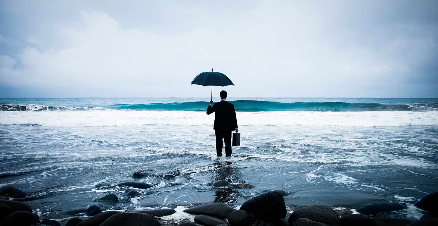 Businessman standing with an umbrella in the ocean